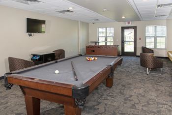 Billiards table in the Cardinal Point game room with a mounted TV and comfortable seating options.